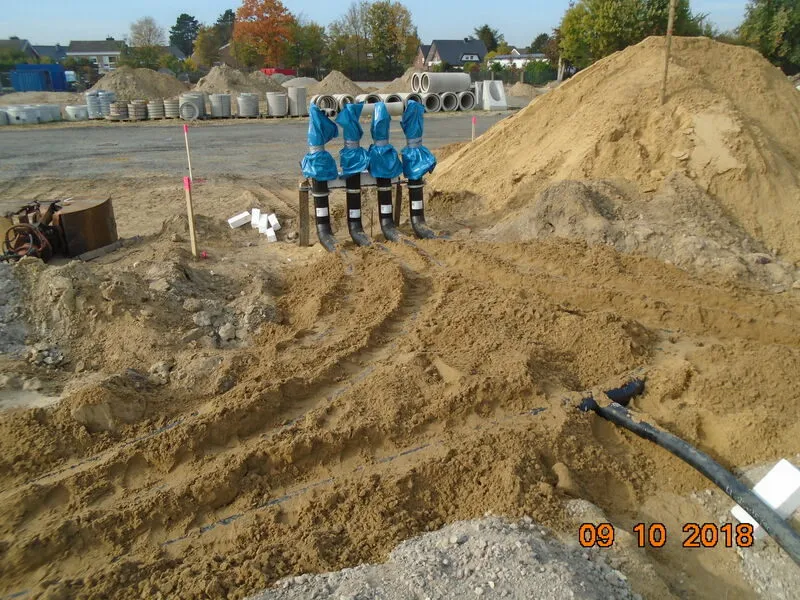 Blaue Hausanschlussarmaturen vor einem Sandhaufen