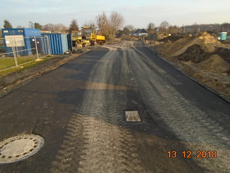 Fertige Baustraße aus Asphalt mit Schachtdeckel