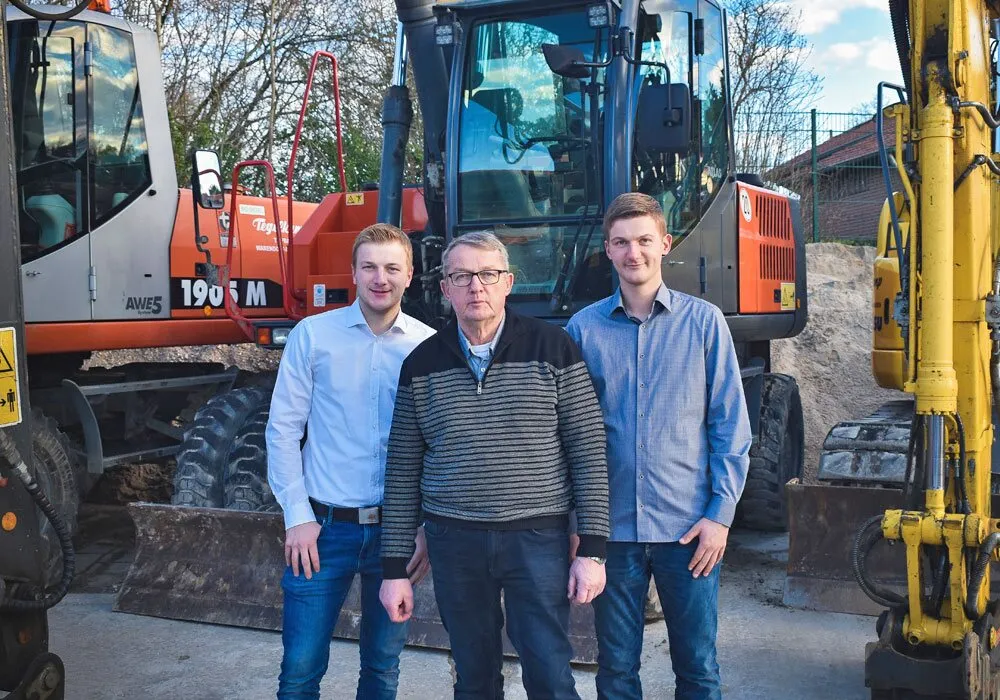 Die Geschäftsführung Edgar, Lars und Tobias Tegelkamp vor einem Bagger