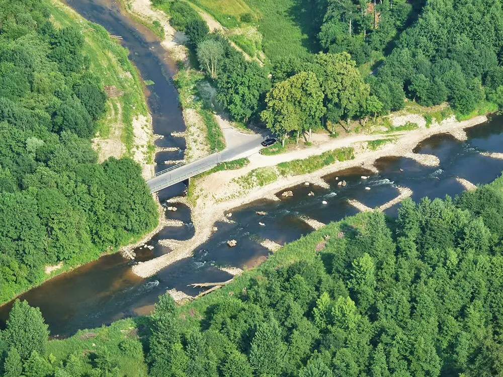 Luftbild eines Flusses mit Steinschüttung und Wald