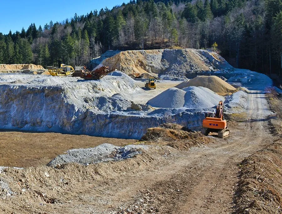 Kiesgrube mit Bagger an einem Waldrand