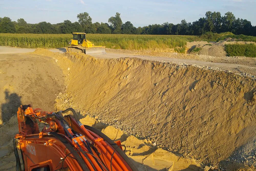 Abbruchkante einer Sandgrube mit Raupe am Horizont