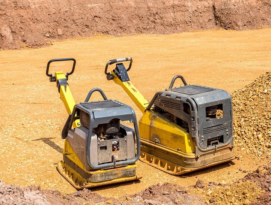 Zwei Rüttelplatten auf verdichtetem Sand